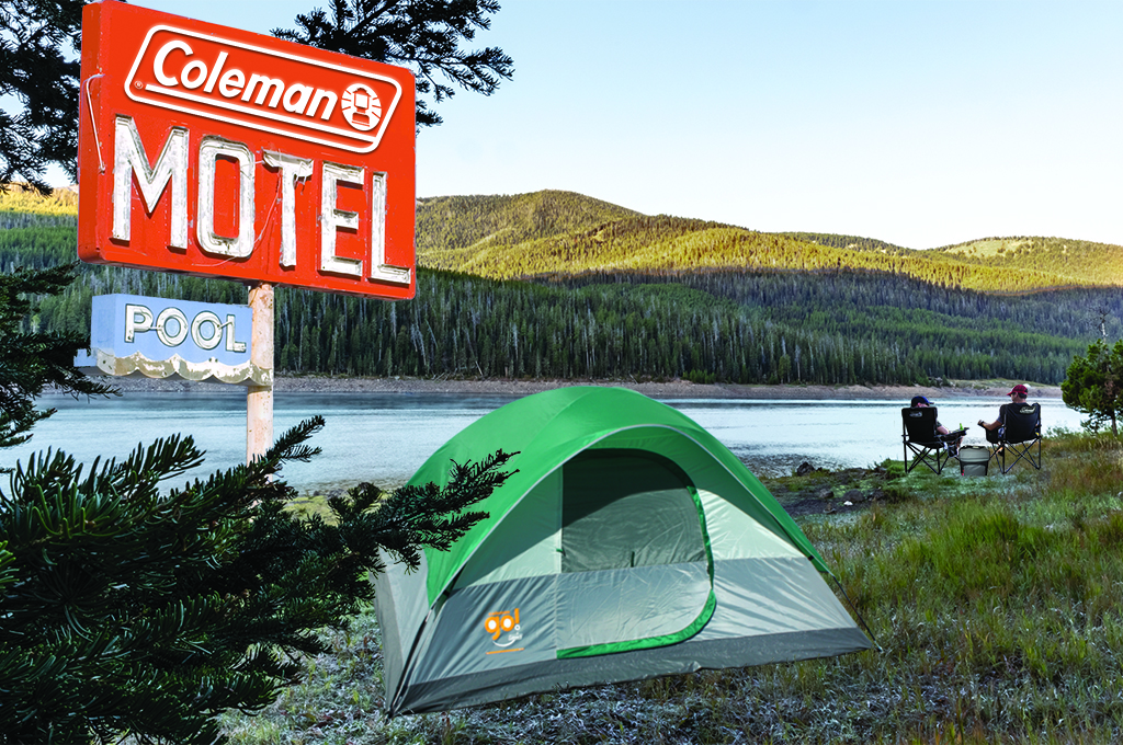 201119_TEM_JC_Coleman Outdoor Hotel3_NG View of Outdoors with mountain, lake and grass in background. Vintage coleman motel sign and coleman tent, 2 people in chairs with a cooler.