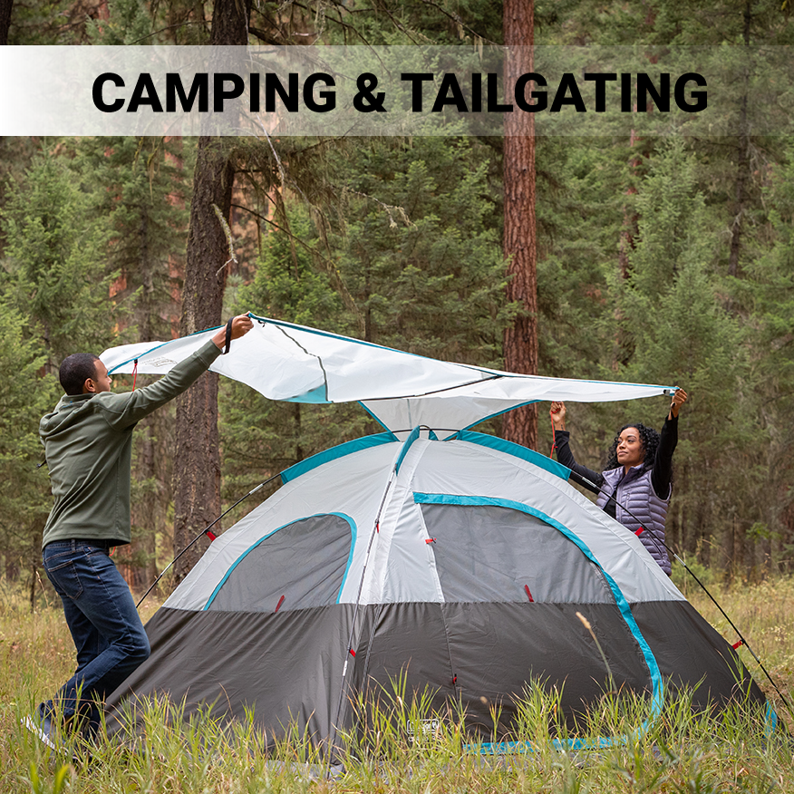 Man and woman putting rain cover onto Coleman OneSource dome tent in the wilderness
